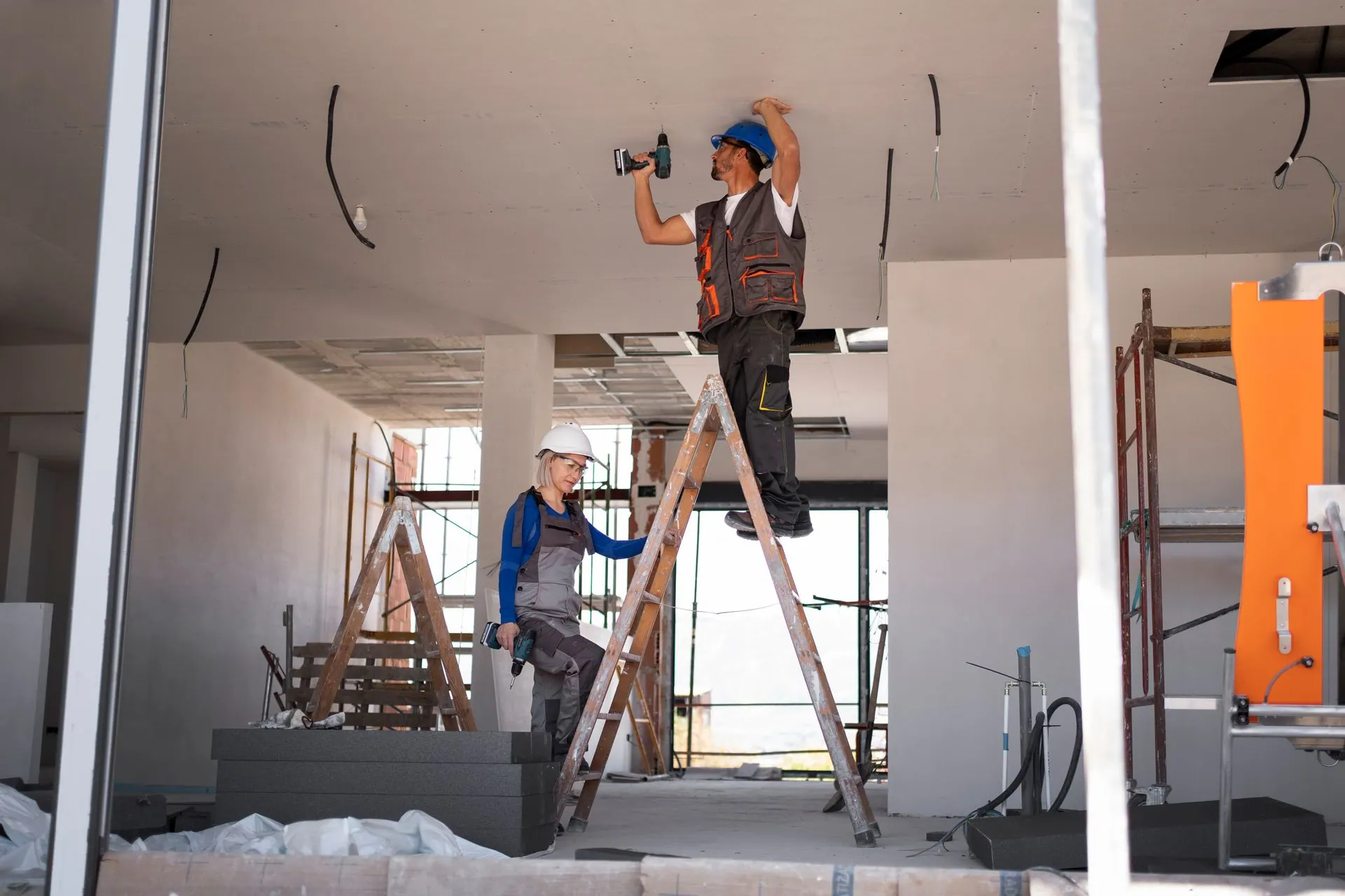 A man is installing a drywall ceiling in a room.