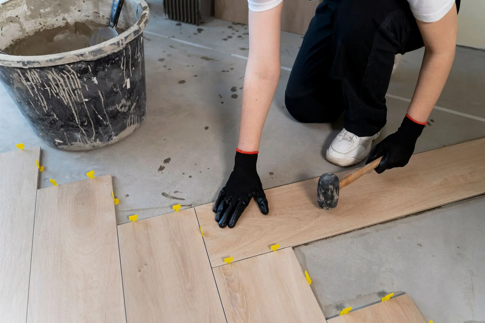 A man is kneeling down to install a wooden floor.