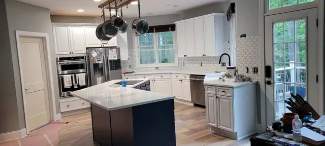 Kitchen remodel with a hanging pot rack over the island, white cabinets, and hexagon tile backsplash.