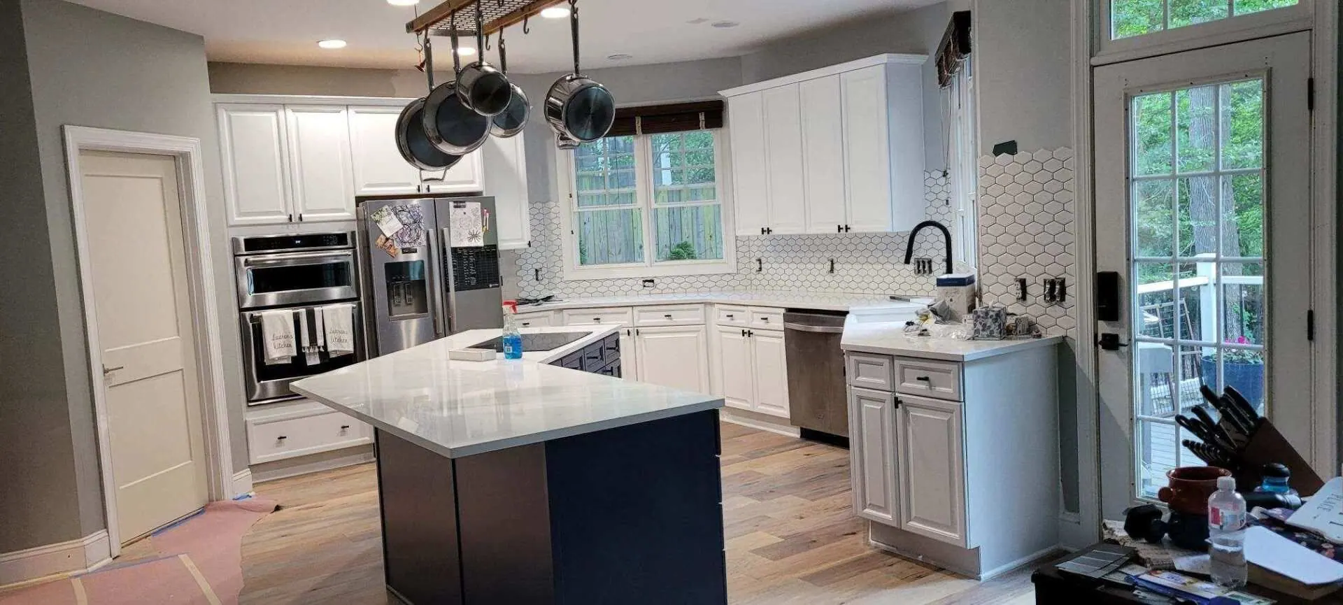 Kitchen with white cabinets, blue island, stainless steel appliances, and a window.
