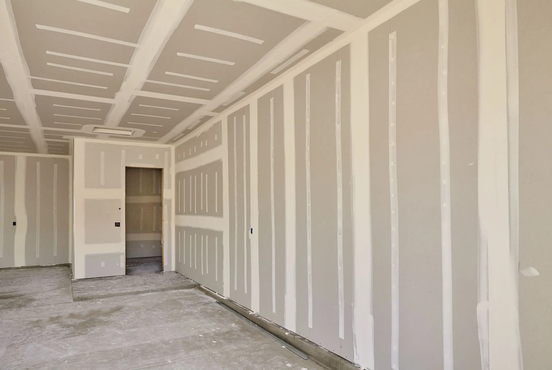 A room with newly hung drywall, the seams taped and ready for finishing.